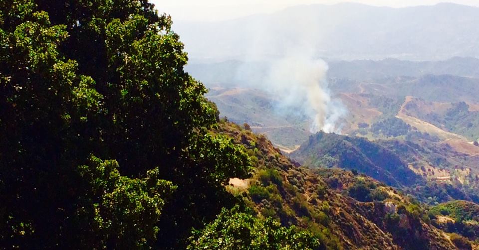 A FIRE JUST BELOW AVATAR'S POINT at Meher Mount in Wheeler Canyon on April 17, 2015. This photo was taken around 11:00 a.m. in the morning. Fortunately, by around 2:00 p.m., the fire was under control and not threatening. But the danger of fire is ever present. You can help reduce the risk at Meher Mount by participating in Trim-the-Trail Day. (Buzz Glasky photo, 2015.)