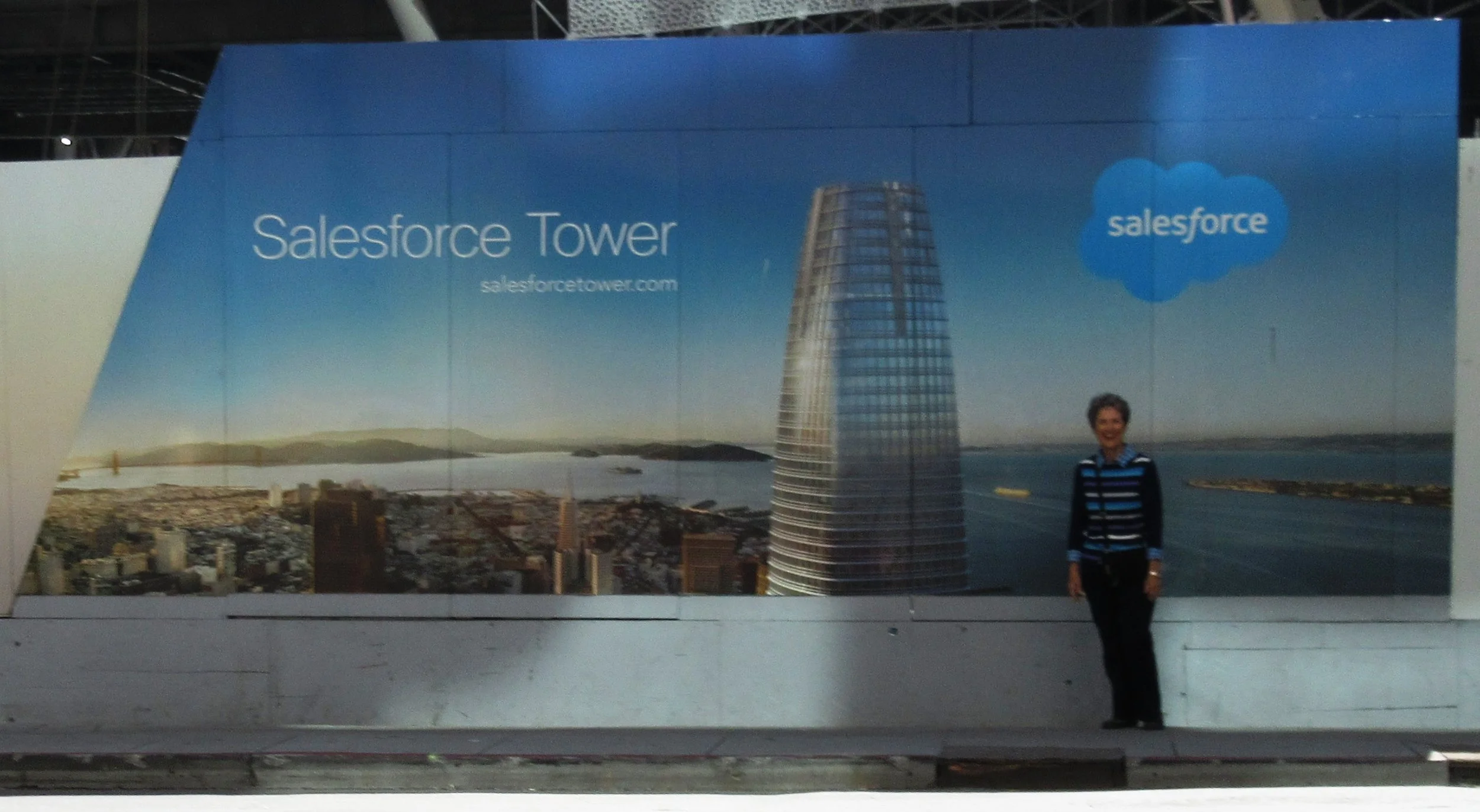 VOLUNTEER DATABASE ADMINISTRATOR Margaret Magnus in front of a photo of the new Salesforce Tower under construction in San Francisco, September 2016. (Photo: Sam Ervin)