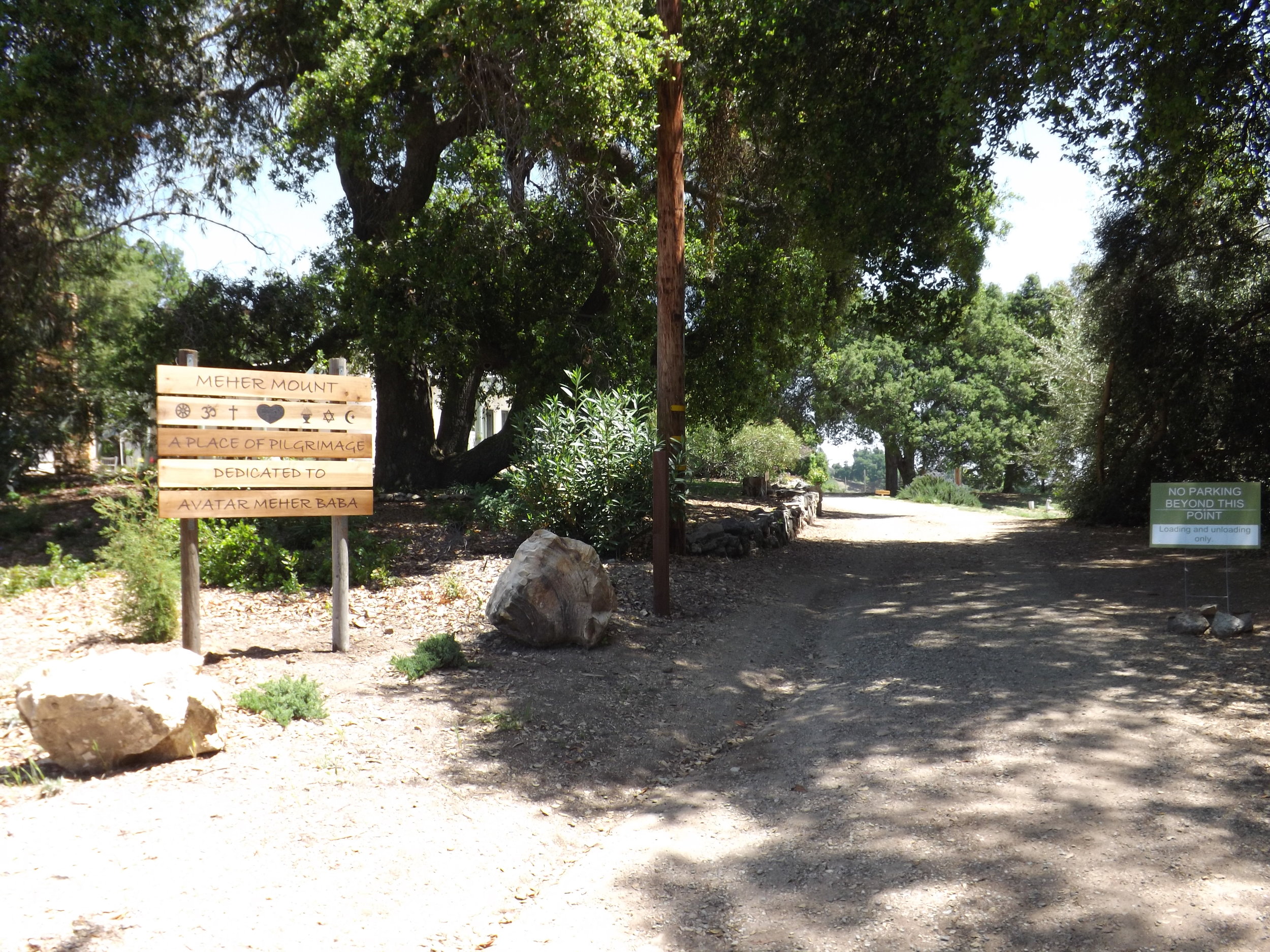 AN ORIENTATION SIGN burned on four-foot lengths of poplar to match the temporary way markers to help orient visitors was created by Manager/Caretaker Leslie Bridget. The six religious symbols are deconstructed from Meher Baba's mastery in servitude symbol. The heart coordinates with the hearts on used on existing signs and the gate. It links the six symbols - one love - one heart. (Photo: Leslie Bridger, 2012).