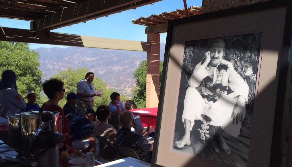 READING FROM Lord Meher at the Gutta Breakfast with a photo of Avatar Meher Baba in the foreground. (Photo: Buzz Glasky, 2014).