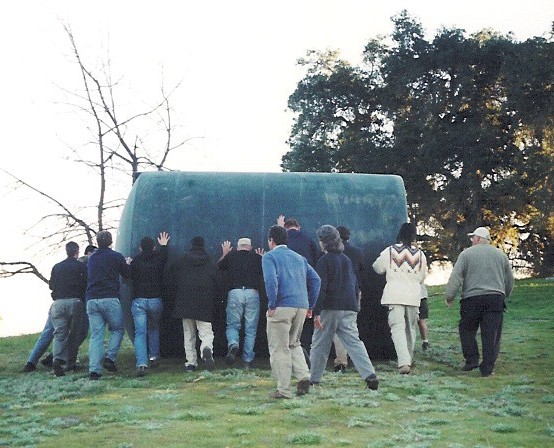 MANY HANDS MAKE LIGHT WORK. When the then new water system was being installed in 2004, a group of volunteers joined together to roll the water tank up the hill to sit beside the pool. Because so many joined the effort, it was almost effortless. (Photo: Sam Ervin)