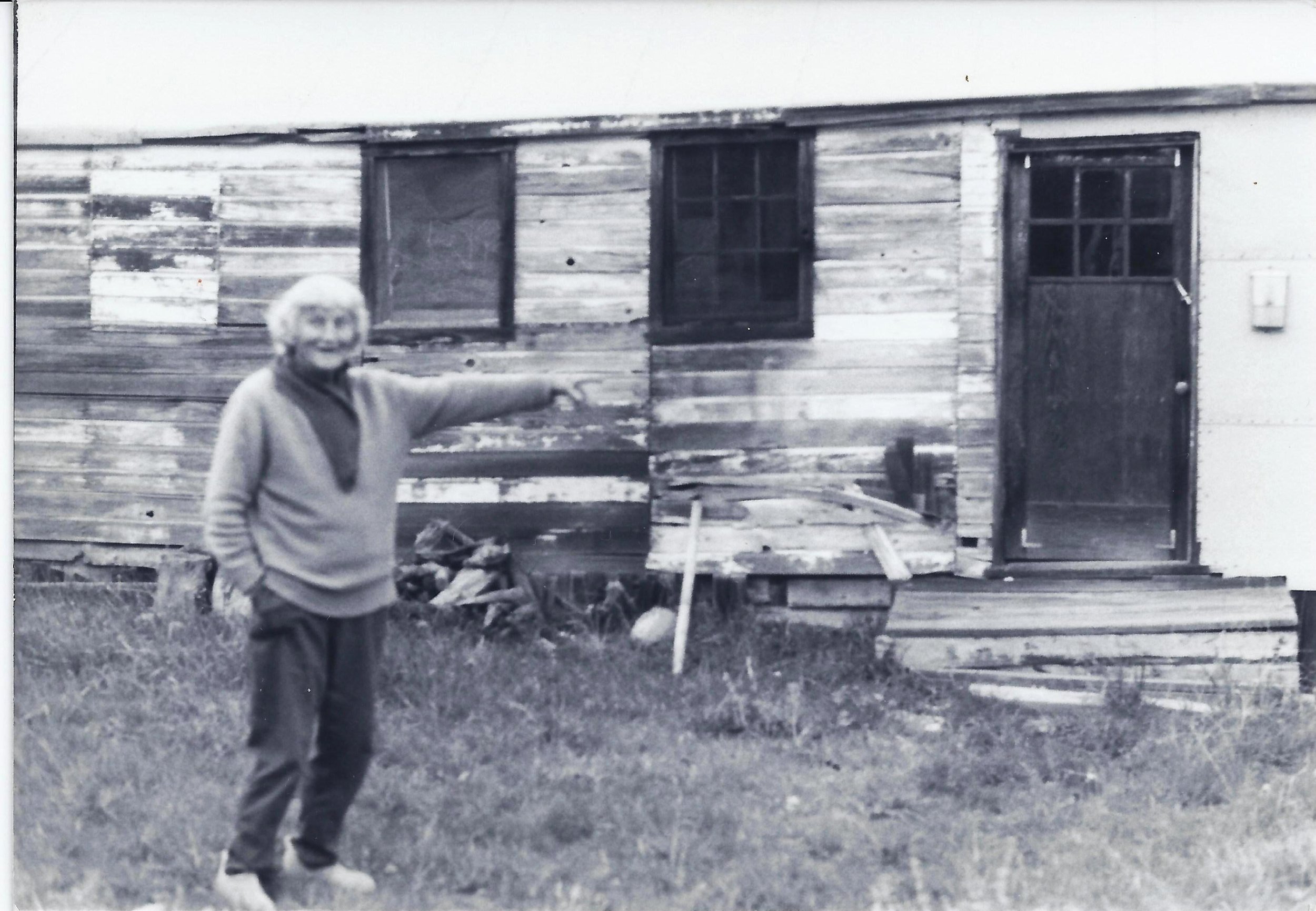 AGNES BARON, the caretaker of Meher Mount, pointing to the carpenter's shed, known as "the white house," which was brought on the property to house the men mandali traveling with Avatar Meher Baba's for His planned 10-day stay in 1952. He did not arrive at Meher Mount in 1952 due to the automobile accident on May 24 near Prague, OK. 