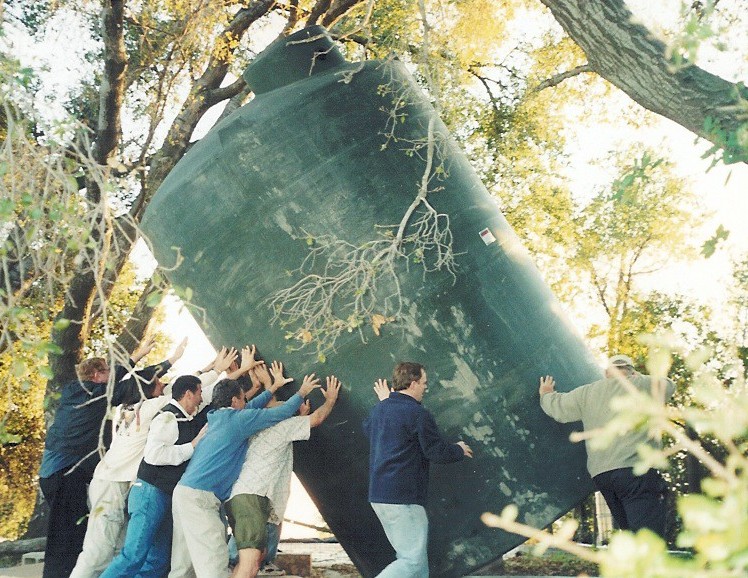 SETTING THE 5,000-GALLON water tank, which was part of Weeds 'n' Water, in place near the swimming pool/water reservoir. These volunteers were at Meher Mount in February 2004 participating in a long-range planning community meeting. They took a break to install the tank. (From left to right: Fred Stankus, Ray Johnston, Jamshid Ebrahimzadeh, Jim Auster, unknown, Merwan Scott, and Marko Swearingen.) (Photo: Sam Ervin, 2004)