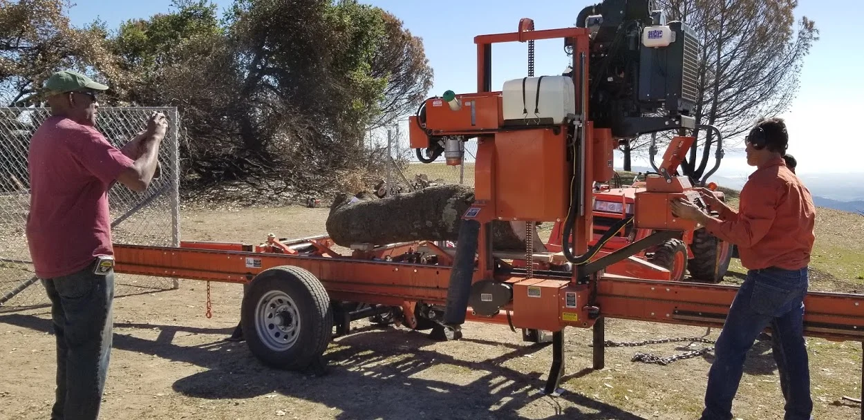 HAROLD GREENE (left) documenting the milling process while Peter Harnisch (right) handles the portable sawmill he brought to harvest the fallen wood from Baba's Tree at Meher Mount. (Photo: Margaret Magnus, February 5, 2018) 