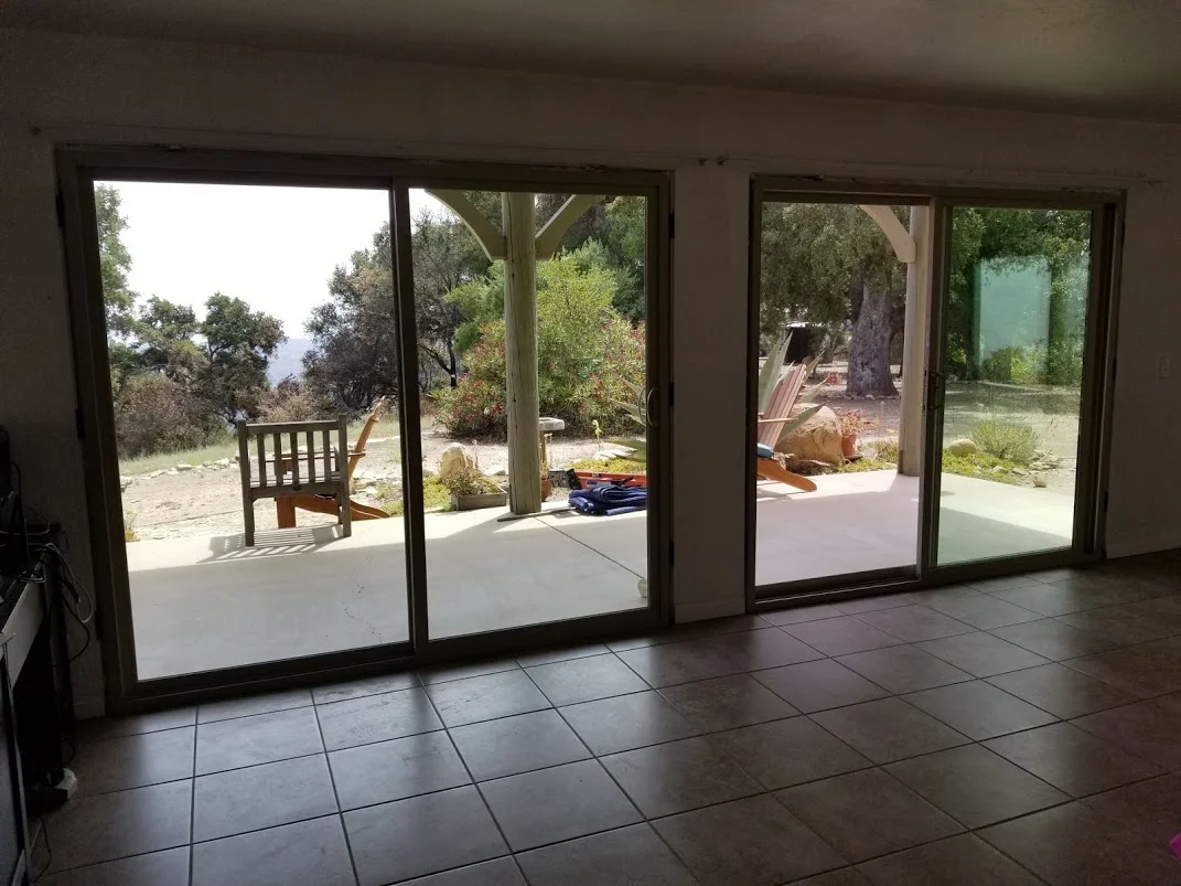 SLIDING GLASS DOORS replace the French doors and side windows to open up the views to the outside and bring in more light in the Visitor Center/Caretaker Quarters at Meher Mount. The 25-year-old wood-frame doors are replaced with tempered glass, vinyl-frame doors. (Photo: Margaret Magnus, July 11, 2018)