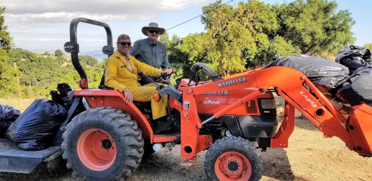 OFF TO MOW some of the more remote access fields of Meher Mount that are near the homes of Meher Mount’s neighbors. Ray Johnston, driving the tractor, and Sam Ervin. (Photo: Margaret Magnus, May 20, 2019)