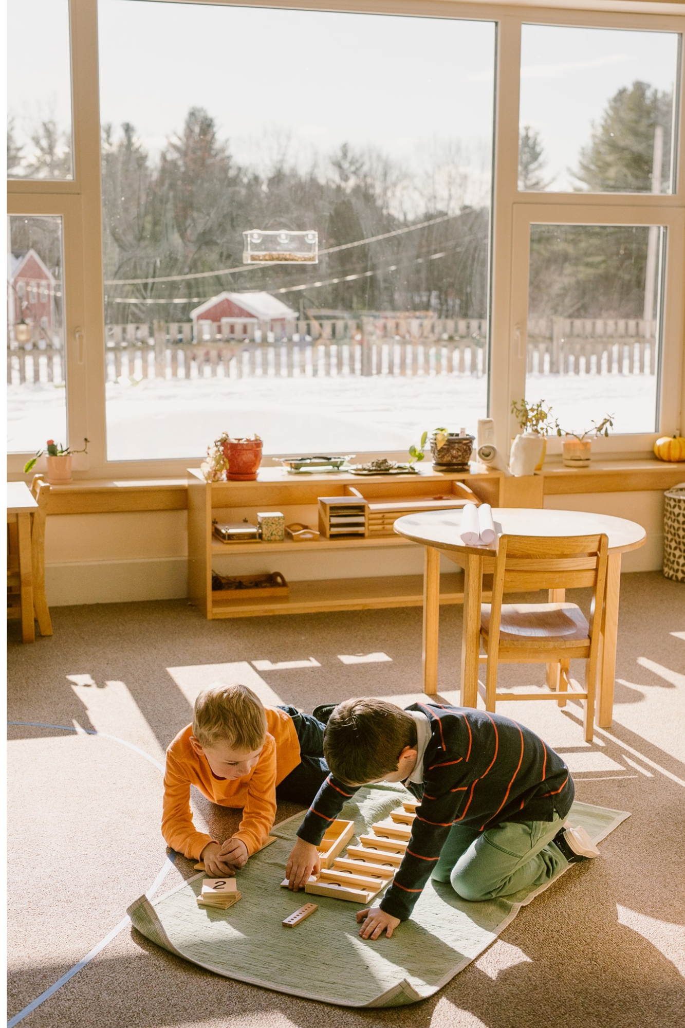 Photo of 2 children's house students working on tens board.png