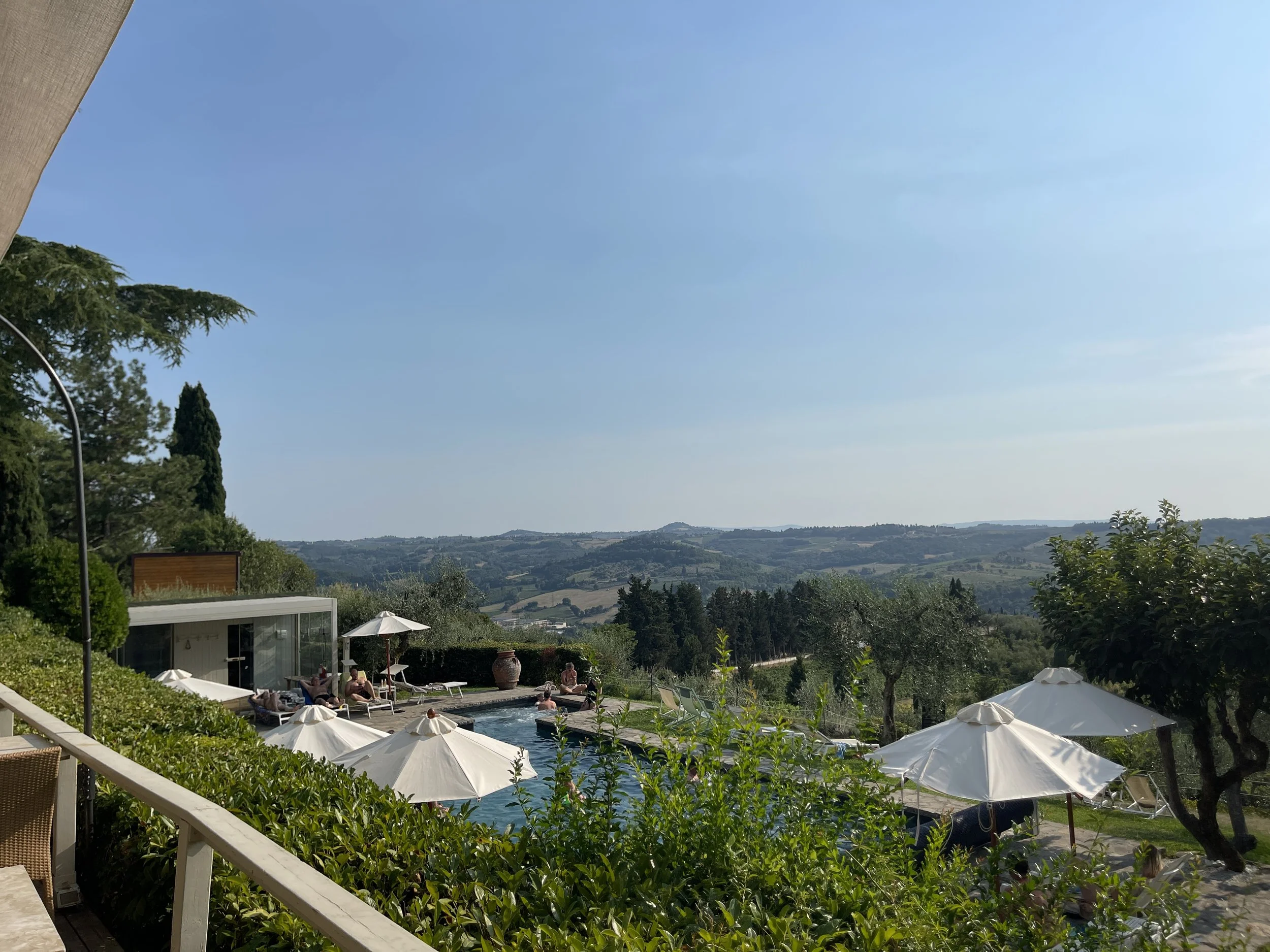 Utsikt over toskanske åser og olivenlunder fra et bassenghotell i Toscana