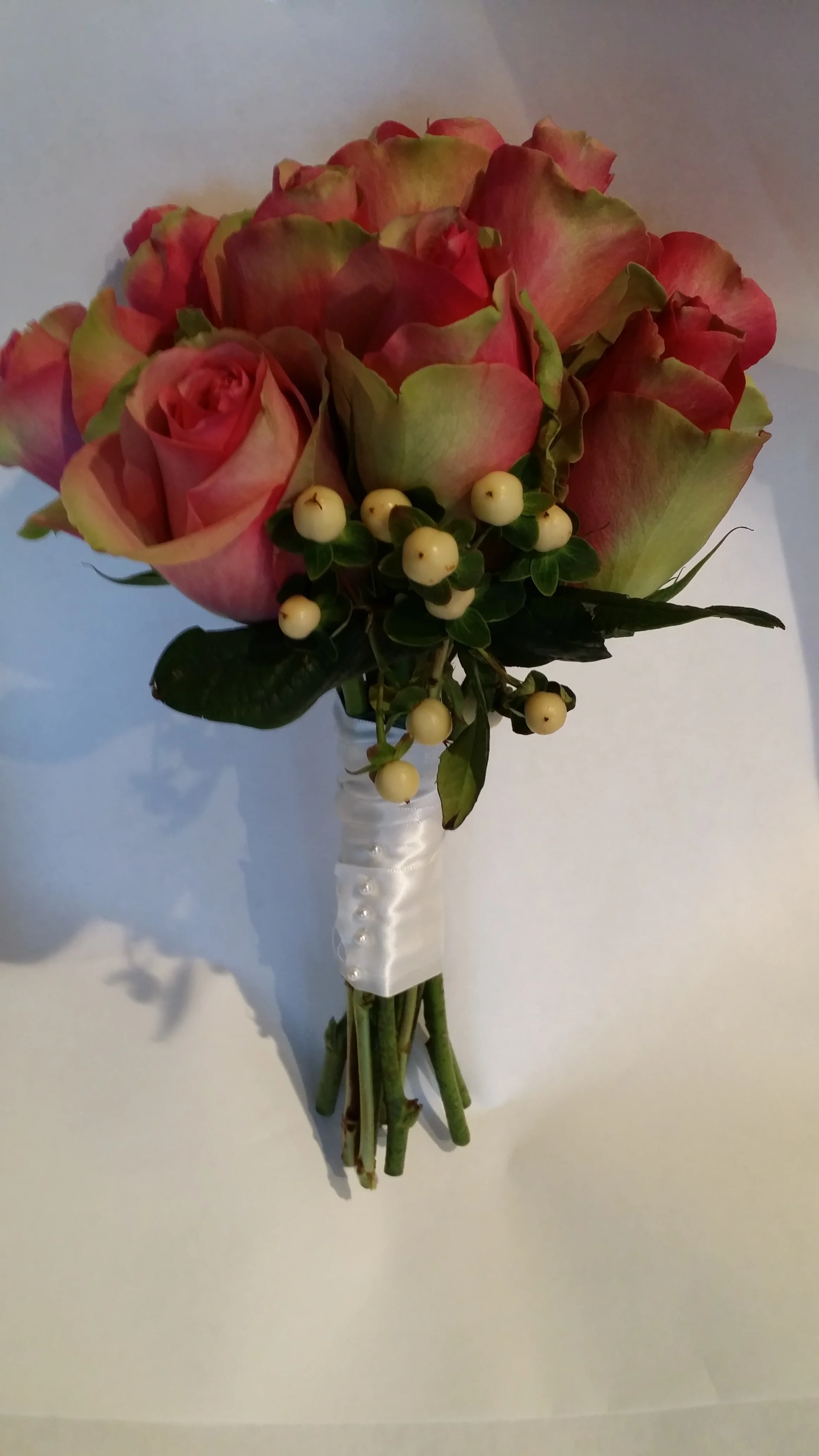 A simple bouquet featuring "Belleview" Roses, and white "Hipericum" berries