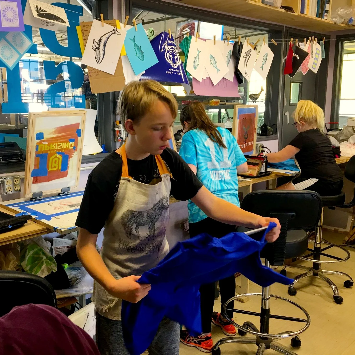 Students work with screens and shirts in the design studio.