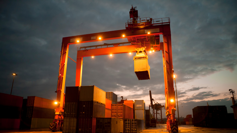 A shipping container crane at sunset