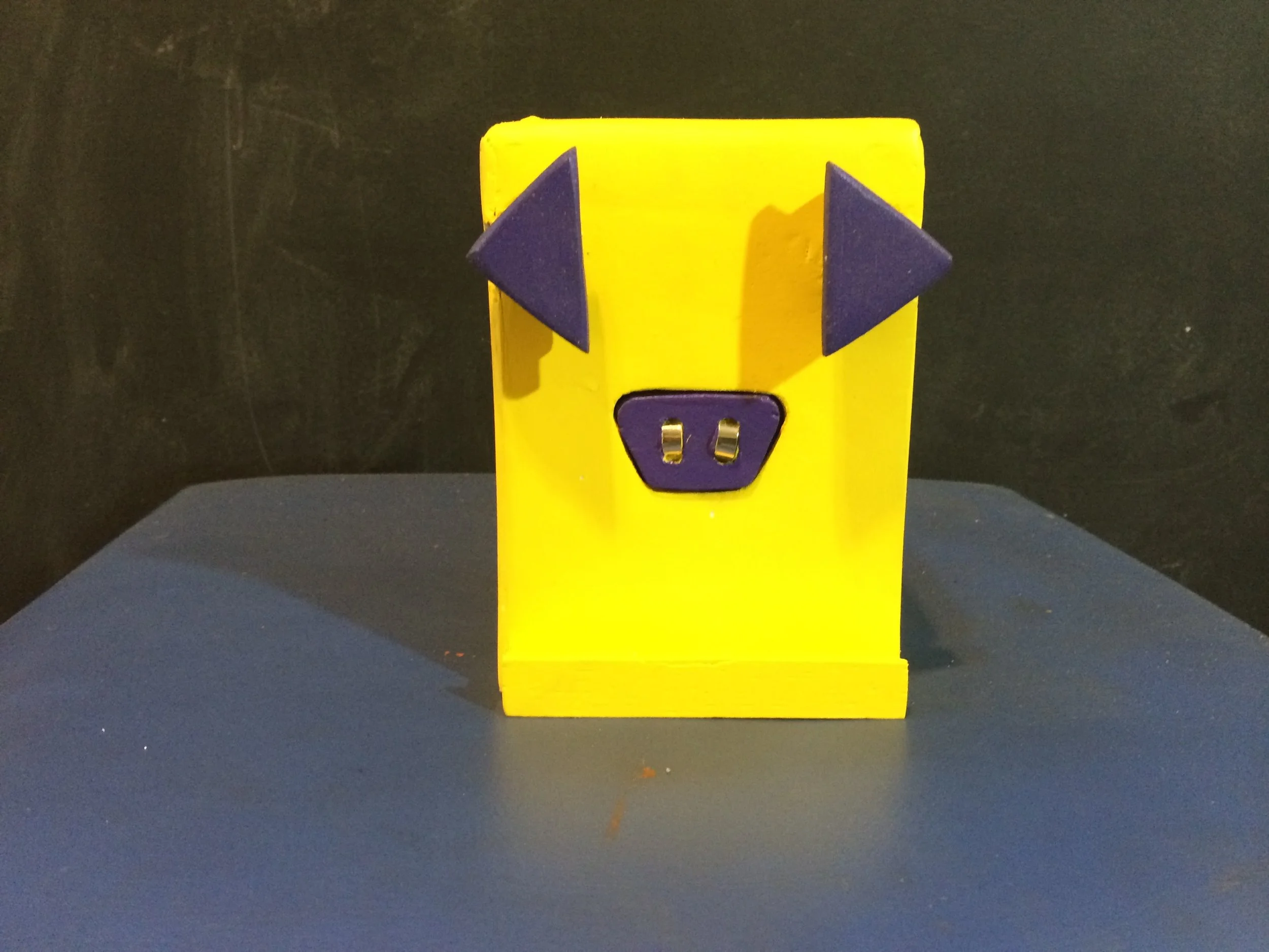 Sem o celular, o porquinho continua com o fucinho mas agora na função liga e desliga, como um botão. Apertou o fucinho, liga o cofre e ele sabe que o celular está encaixado.