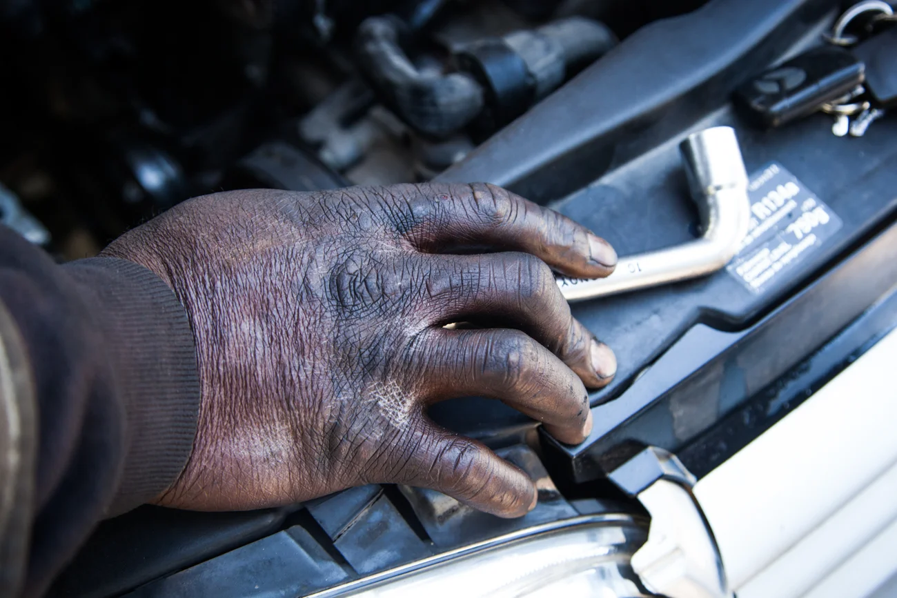 A Aubervilliers, dans le quartier du Landy, tout près du foyer africain de la rue des Fillettes, plusieurs mécaniciens formés en Afrique de l'Ouest proposent leur service à la population. La rue Germaine Tillon abrite l’un des plus grand garage à ciel ouvert d’Ile de France. On repart à même le trottoir. Toutes les cylindrées peuvent être réparées. Chaque mécanicien a sa spécialité, son savoir-faire. Plusieurs clients confient préférer venir ici pour payer moins cher que dans un garage traditionnel. Les réparations seraient aussi de meilleure qualité. Ces hommes aux mains pleines d’huiles ont entre 25 et 45 ans. Arrivés principalement de Côte d’Ivoire du Mali et de la Guinée Conakry, ils connaissent des difficultés pour régulariser leur situation administrative. Leur revenu quotidien varie selon les clients et la tolérance des policiers qui rodent. Parfois, certains confient qu’ils se font confisquer leurs outils par les autorités. A d’autres moments, ce sont les clients qui tentent de partir sans les payer. Malgré tout, ces hommes sont fiers d’exercer ce métier pour survivre à la périphérie de Paris. AUBERVILLIERS, Dimanche 19 avril 2015.