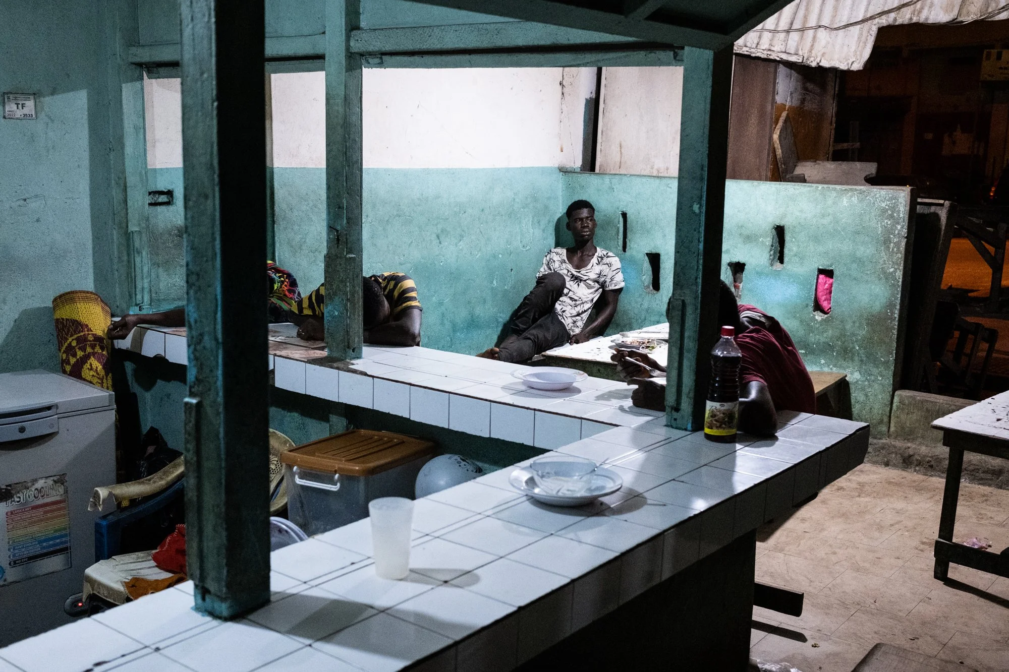  Il 5H00 du matin au kiosque d’Abou. Les derniers pain-omelettes et spaghetti-rognons ont été servis. D’ici une heure, les premiers travailleurs des 220 logements arriveront pour prendre leur café au lait du matin. Adjamé. Juin 2023.  