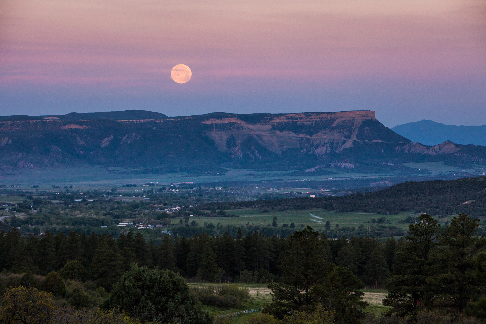 The moon sets over Mesa Verde National Park, while a light mist rolls through Mancos Valley.