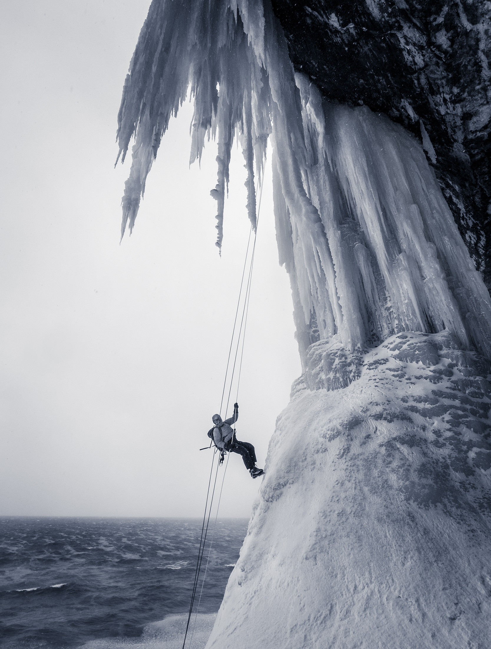An ice climber rappels down Dairyland over the open water of Lake Superior.