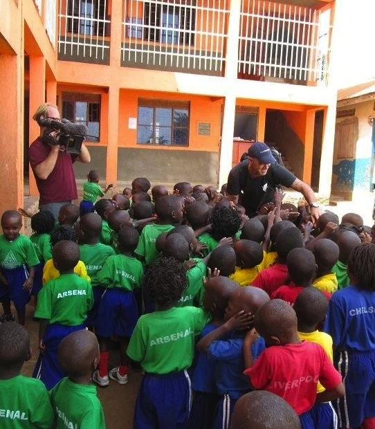 A "Dangerous Grounds" cameraman captures Todd Carmichael greeting students at Trinity Children's Centre.