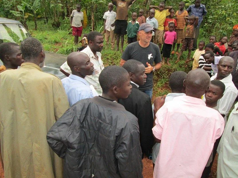 Accompanied by Trinity Children's Centre founder Romans Serunjogi, Travel Channel host Todd Carmichael negotiates with local farmers at a coffee farm in Bulago, Uganda.