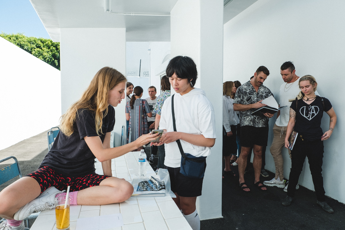  Fans in line to have their copies of “ Why Be You When You Can Be Me? ” signed by the artist at Dover Street Market Los Angeles.  Original story via  Office Magazine  