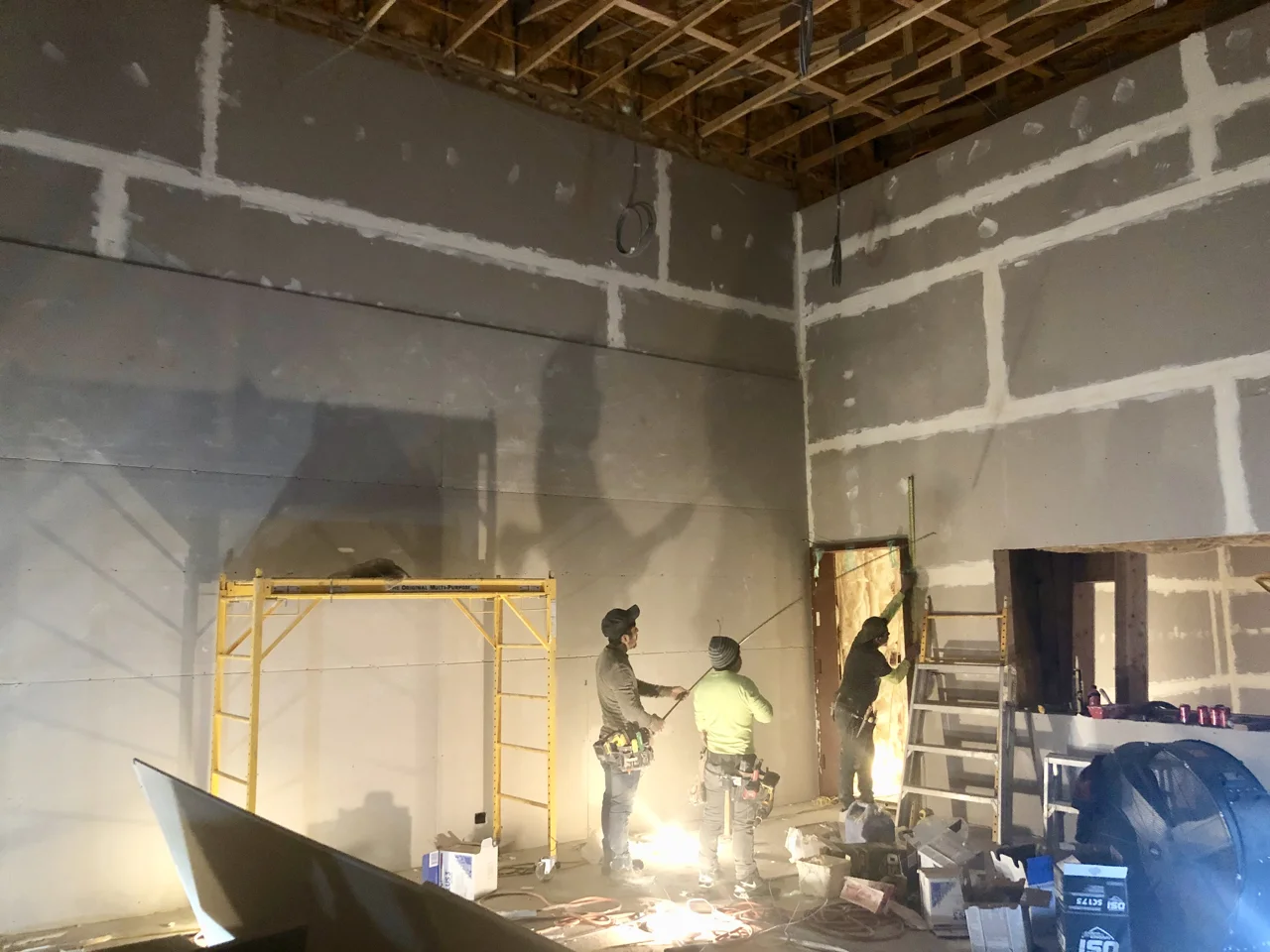 The second level of sheetrock is going up in studio 1. The seems are staggered and the corners are lapped. The opening on the right is the window into control room 1.