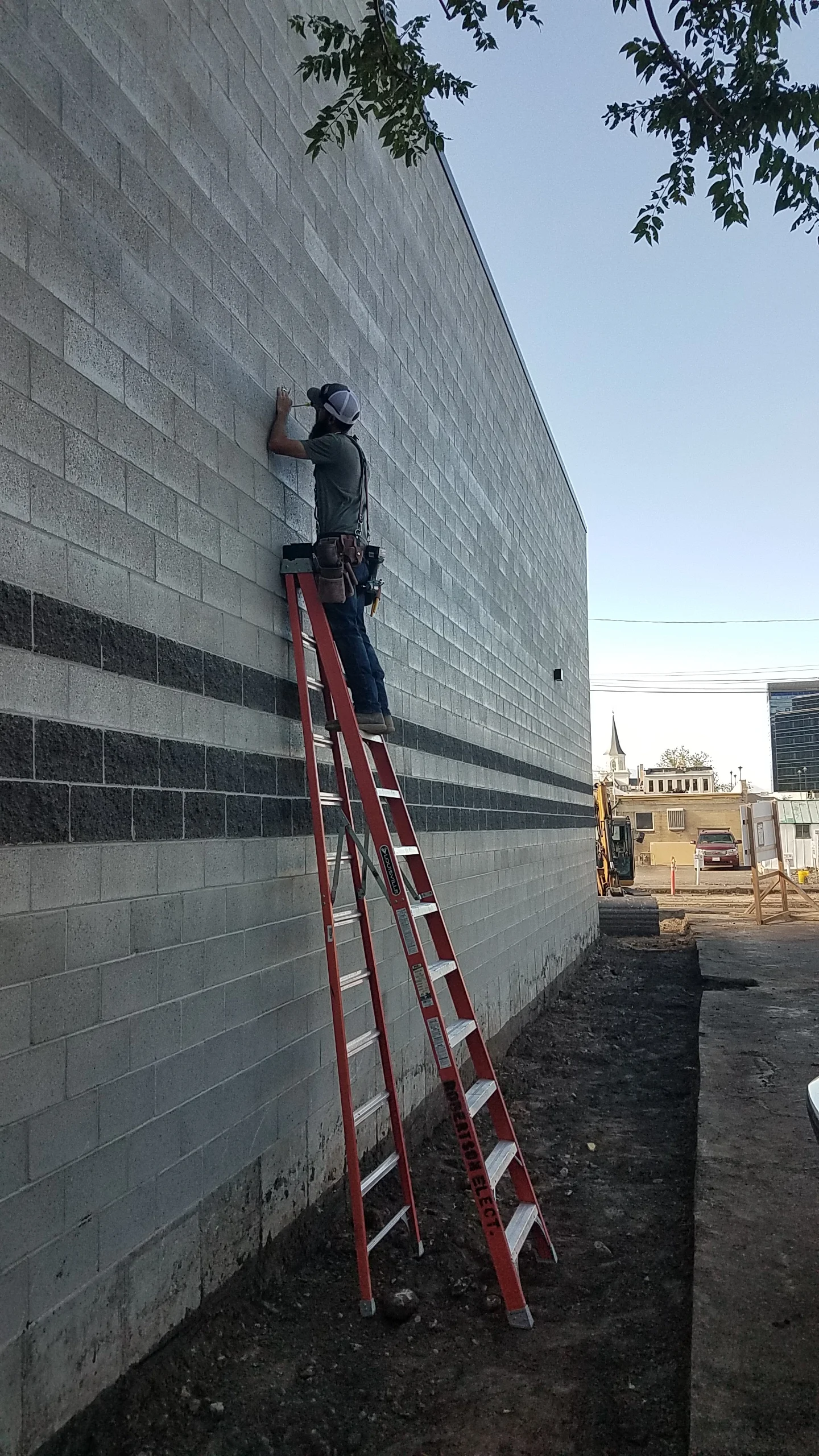 Installing exterior lights along the west wall of the building.