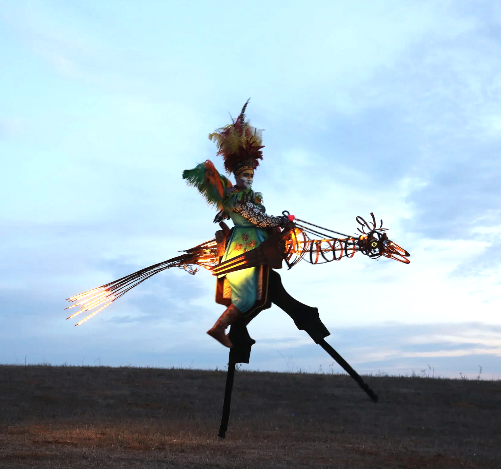 Stilt performer operating a bird stilt puppet during an outdoor street theatre performance