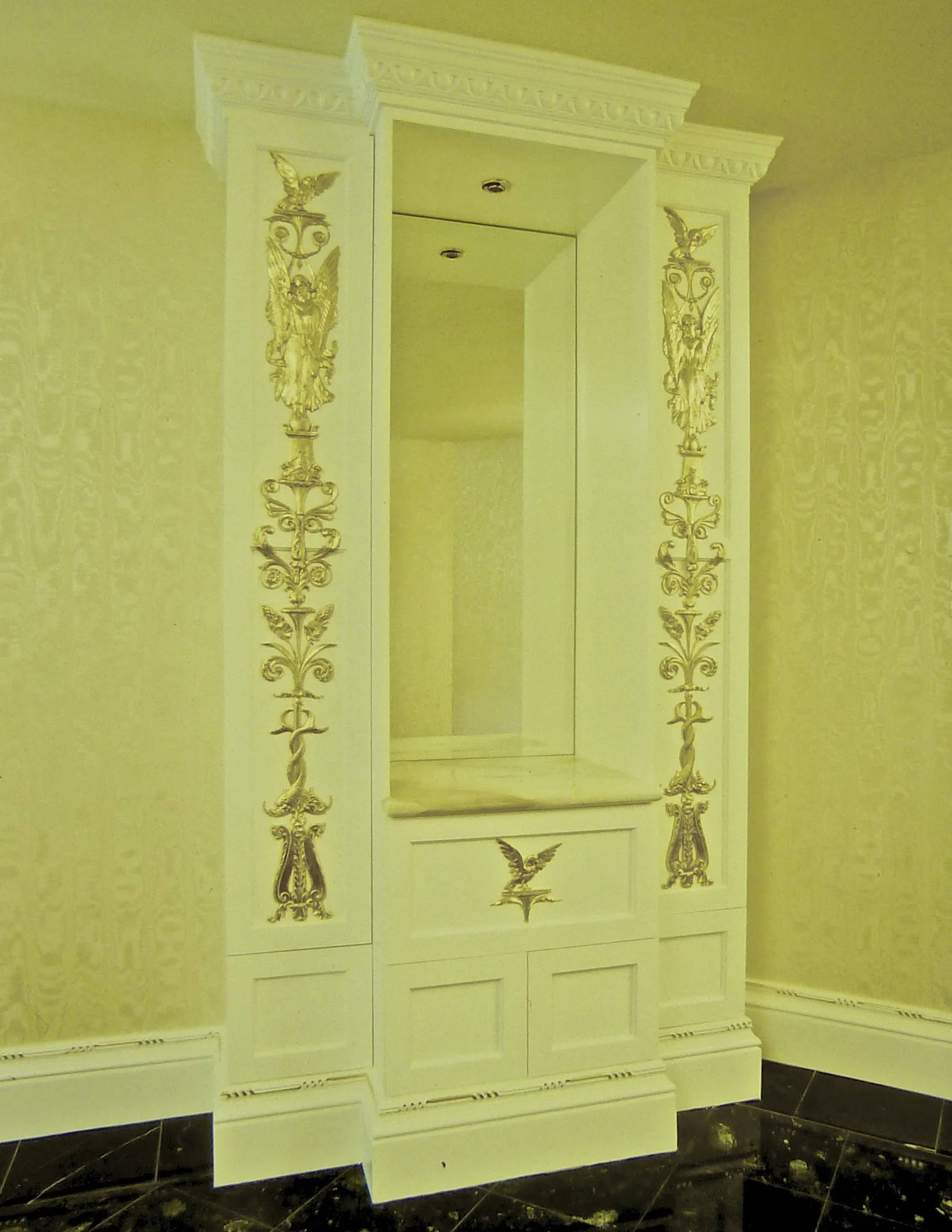 Detail of cabinetry in white for a card room in the neo-classic style with 24k gold accents.