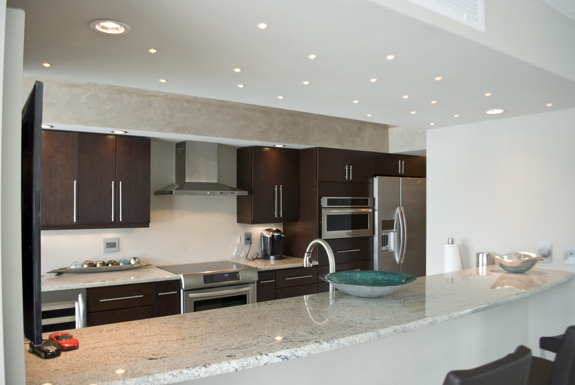 A view through the bar of the modern kitchen with a Venetian Plaster ceiling of this completely renovated condominium.