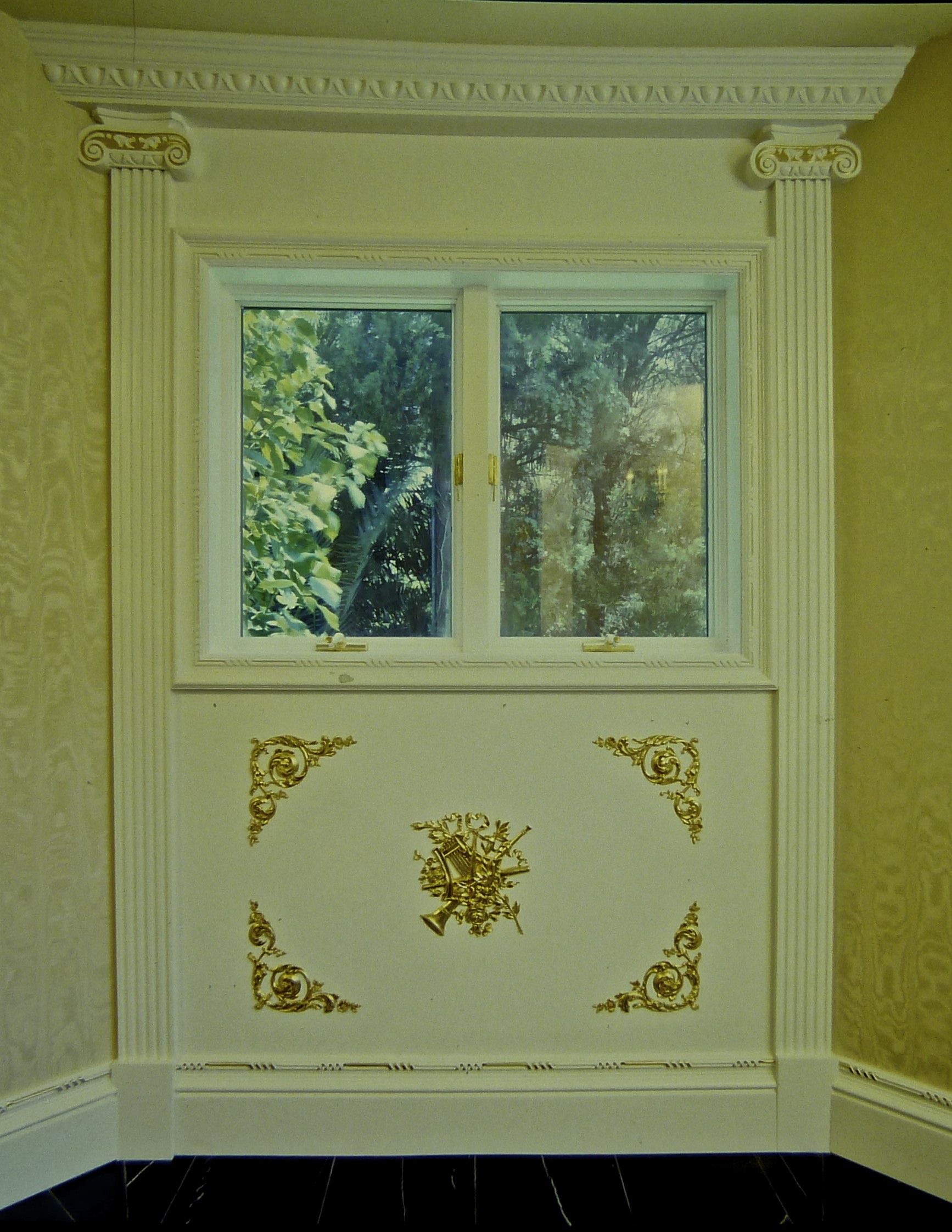 Detail of finished woodwork in white for a card room in the neo-classic style with 24k gold accents.