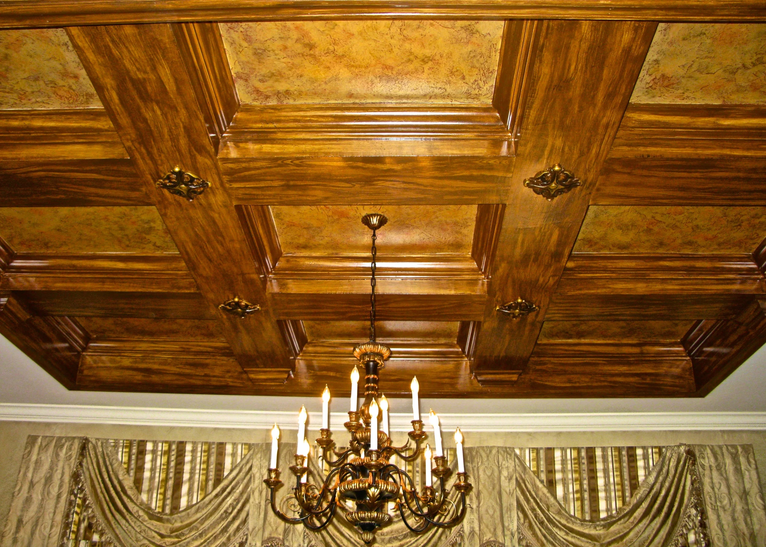 Coffered ceiling with a touch of ornament and gold leaf, with beams finished with faux bois and sponge treatments.