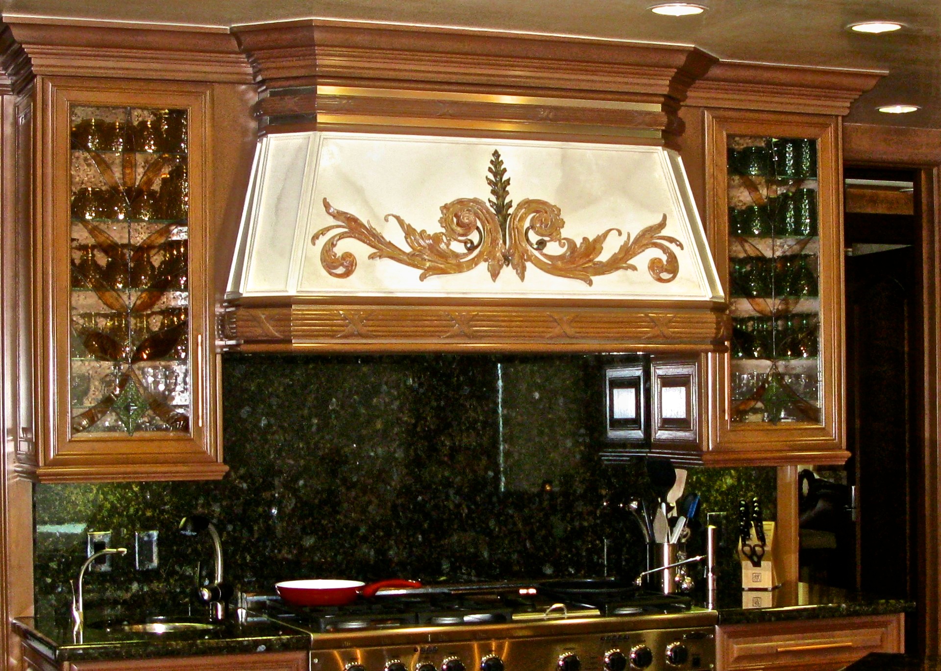 Range hood painted in faux marble with bronzed acanthus leaves in applied ornament.
