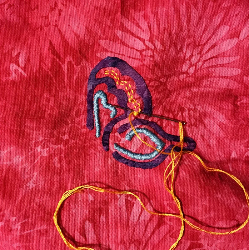Outlining the golden orange wing bit for satin stitch.