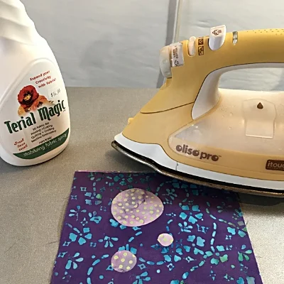 Treating my fused top fabric with Terial Magic spray-on stabilizer for unlayered practice piece.