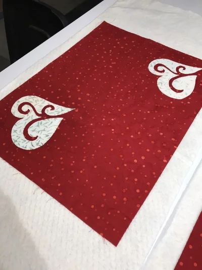 Layer red place mat top with quilt batting and backing for appli-quilting. Hold layers together with spray adhesive. I used 505.