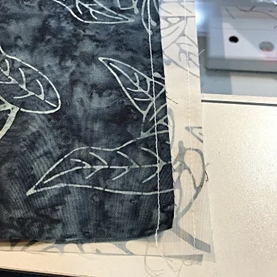 stay stitch 1/4" from the raw edge on one side of each napkin square.