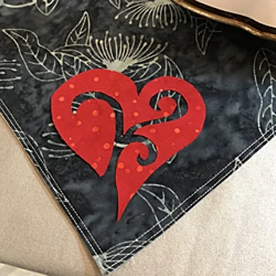 Peel fusible paper off of red heart and position 1/2" from napkin edge.