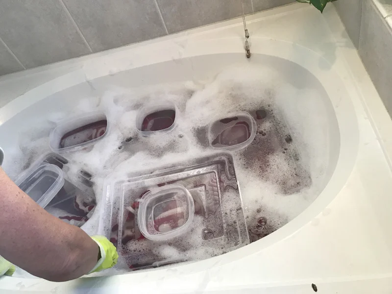 The 2nd soak. Red & White Explosion is weighted down by plastic bin lids laden with tupperware containers filled with water to keep the quilt completely submerged.