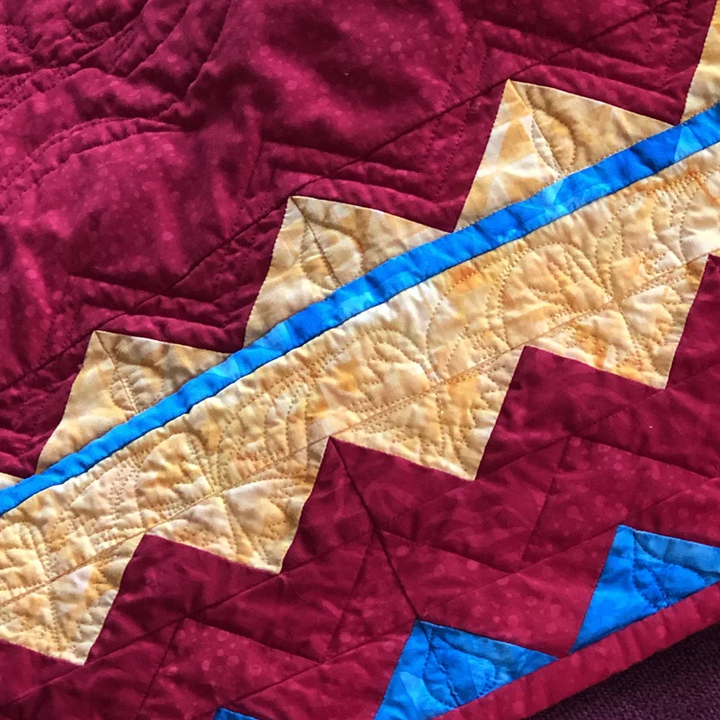 Border created with flying geese and paper-pieced zig-zag blocks.