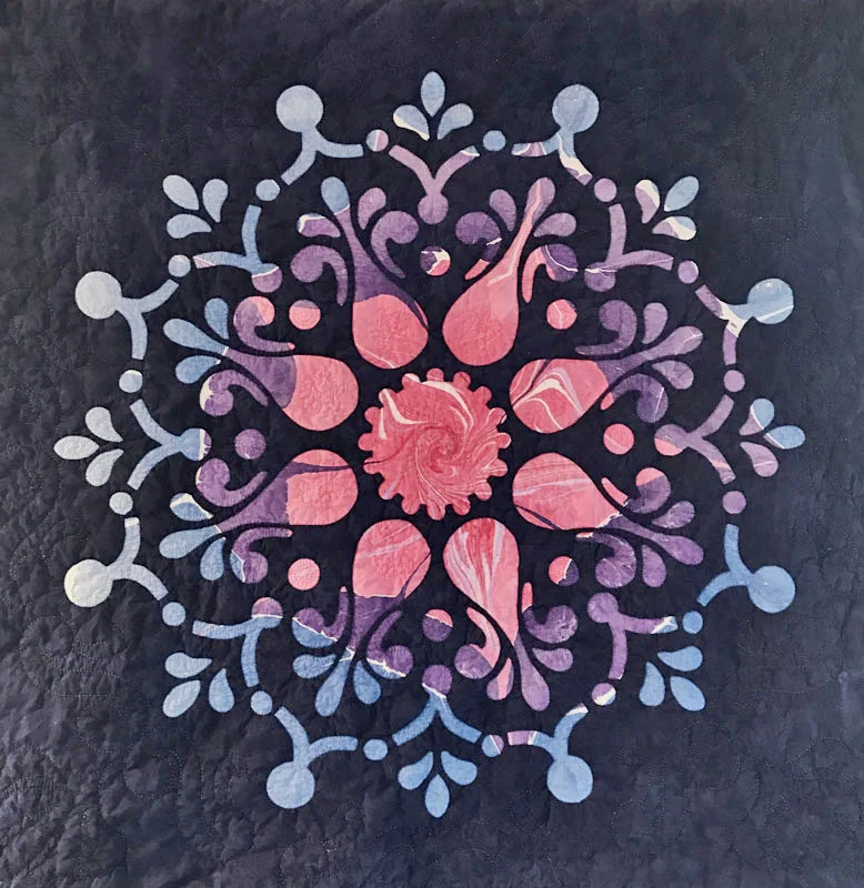 Remembrance, Medallion XIV (36” x 36”) Hand reverse applique, hand quilted in the ditch, scupting the interior space and using the pattern shapes and fabric for quilting ideas. Background is a hand marble by Paula Lavendar, top fabric by Cherrywood Fabrics.
