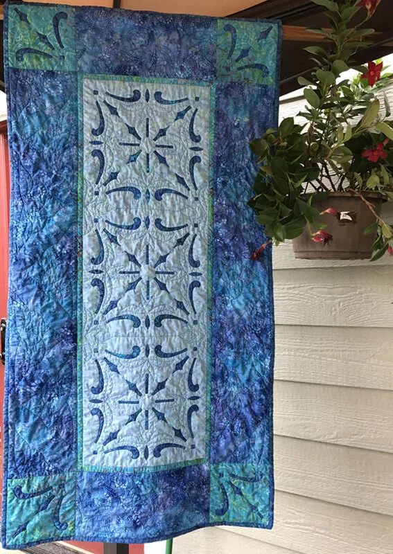 Pacific Splash table runner X (25” x 49”) for hand or machine reverse applique. This was first published in Fons & Porter’s Love of Quilting in 2017.