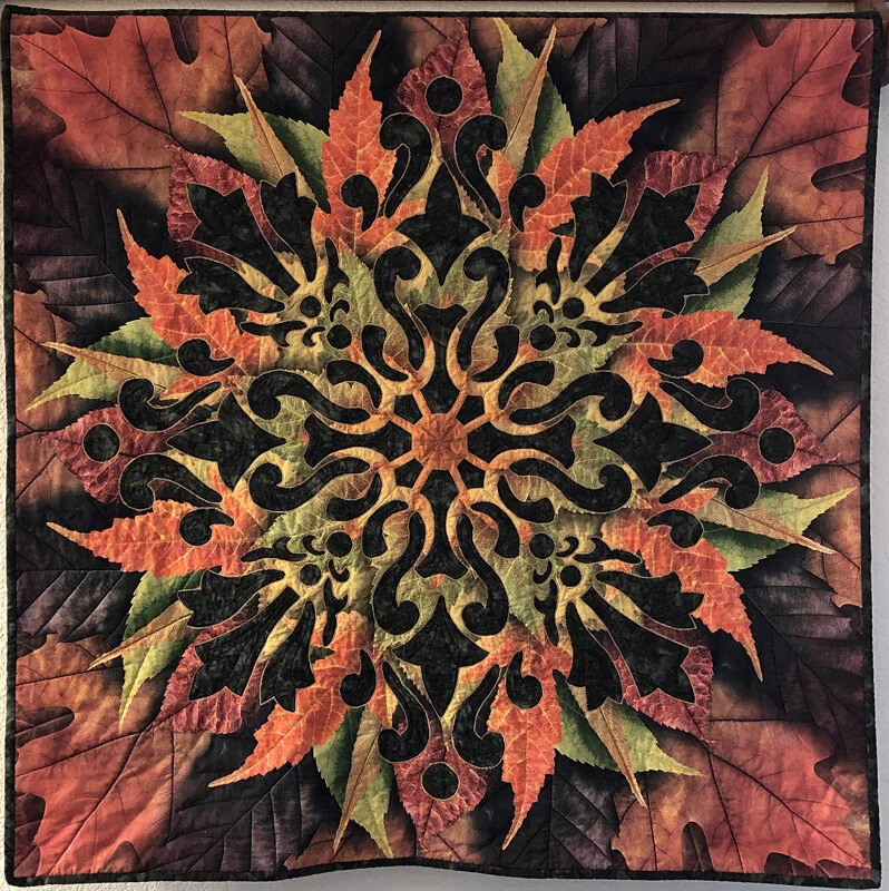 Illumination Medallion X (36” x 36”) for hand or machine reverse applique using a Hoffman Leaf panel as the top fabric.
