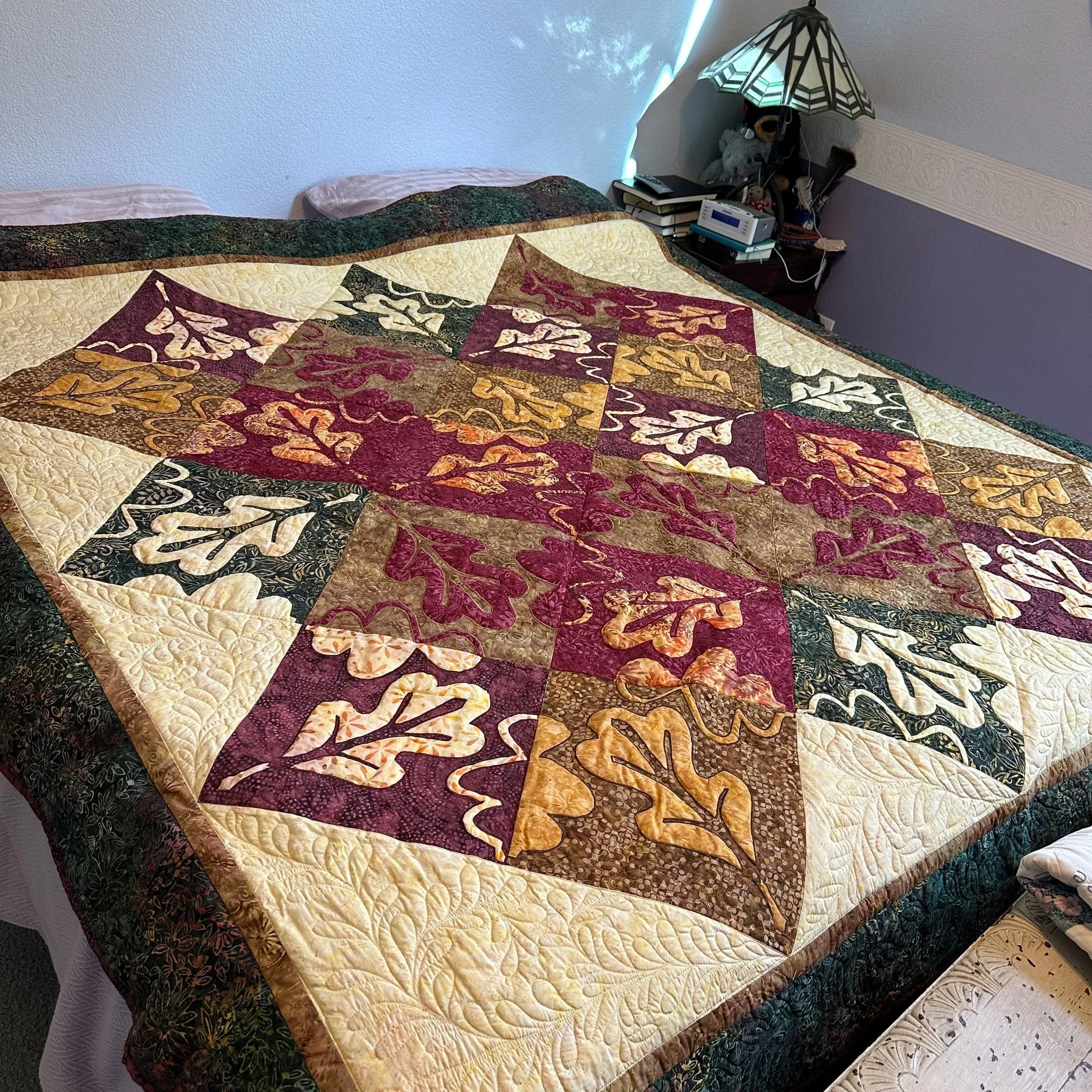 I love the colors of autumn. Enjoying our "Falling Leaves Quilt IX" on our bed right now. Reverse Applique Oak leaves scattered across the top of our King size bed. Designed in batiks by @timelesstreasuresfabrics , 2016. Pattern available o
