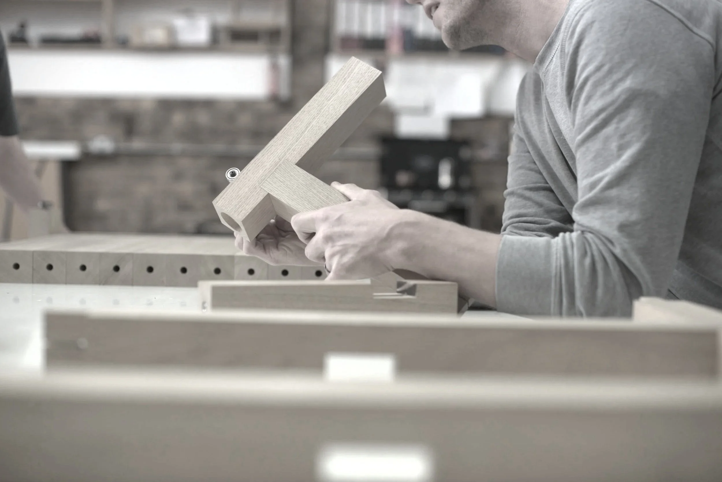 a maker leans on a work bench with a timber component
