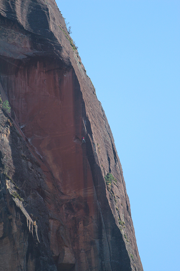 Raul Sauco on development duty on the Black Hole Project. The face on the right is less-than-vertical and coated in lichen, with any face features being highly rounded. The only crack on that face is the barely visible Lost World, which is a very wide offwidth/chimney. On the left, however, the rock is protected by an overhang at the top of the formation.