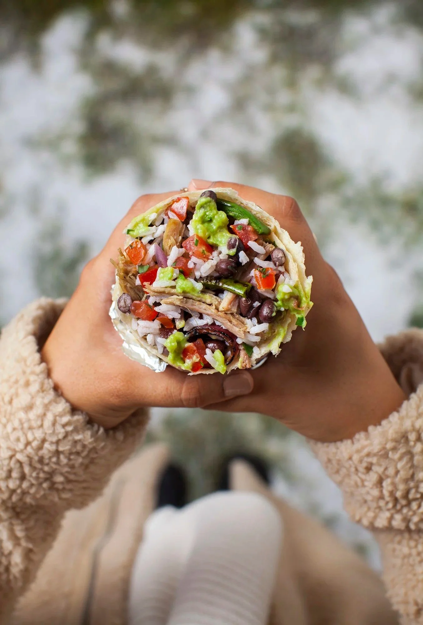 Hand holding a foil-wrapped burrito - delivery app food photography