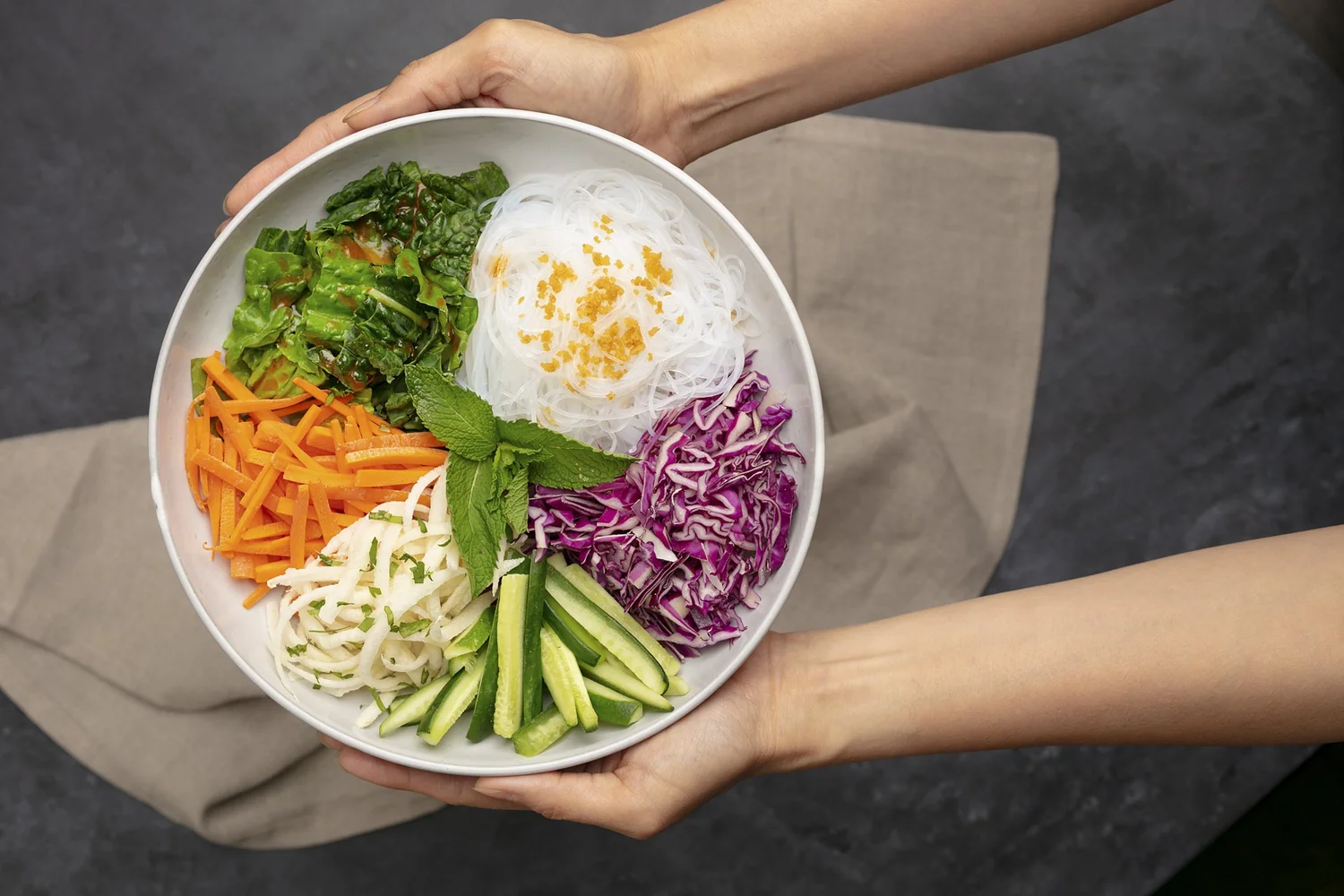 Hands holding a styled salad bowl with rice and fresh vegetables, food styling and product photography, Orange County