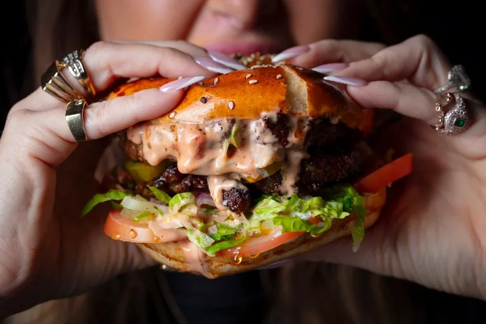 Hands holding a juicy cheeseburger, restaurant food photography with a hand model