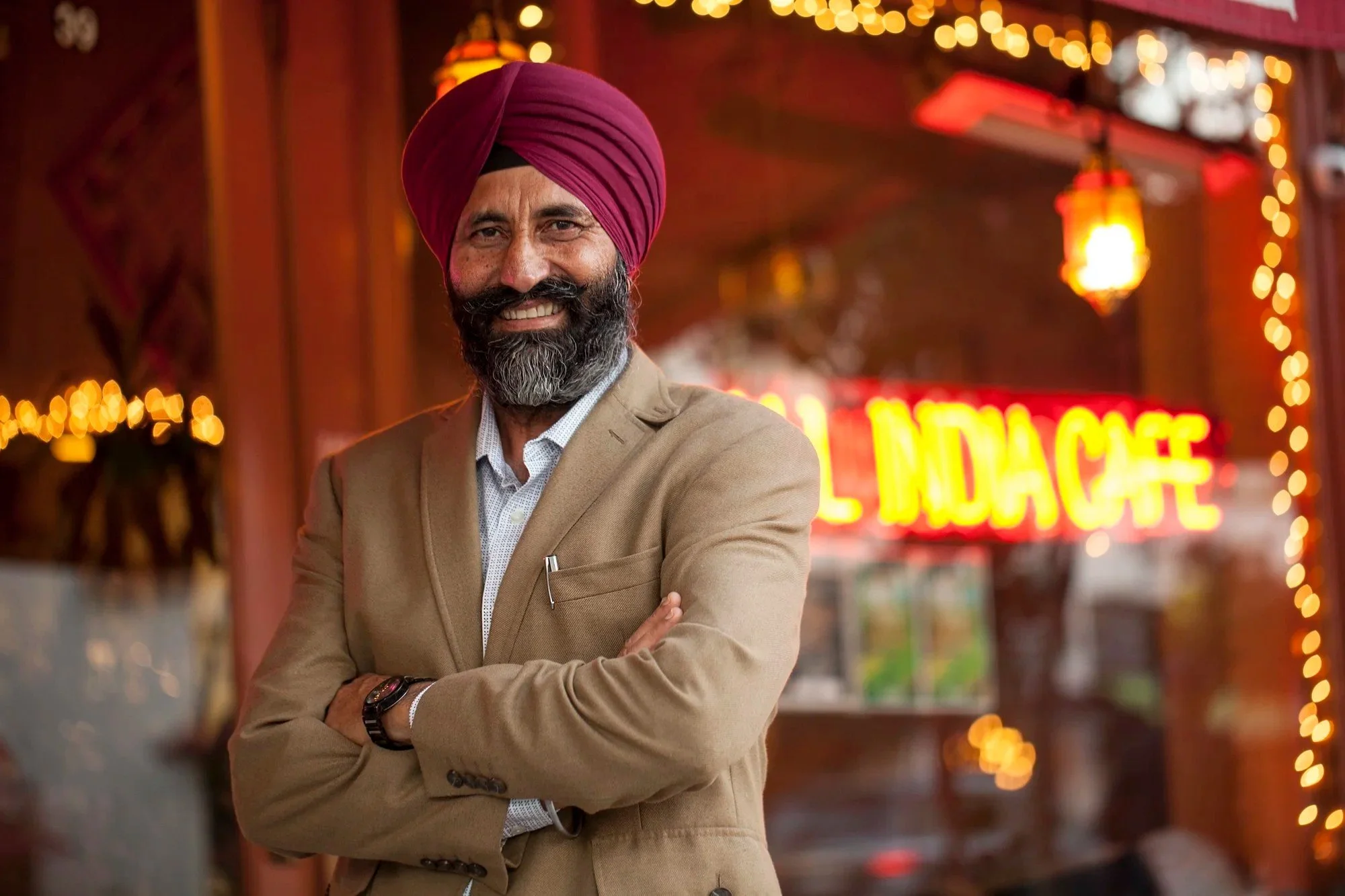 Portrait of a smiling restaurant owner in front of his neon-lit Indian restaurant, restaurant owner portrait photography in Los Angeles and Orange County