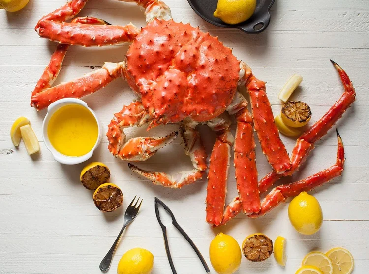 King crab legs with lemon and butter on a white table - soft light food photography
