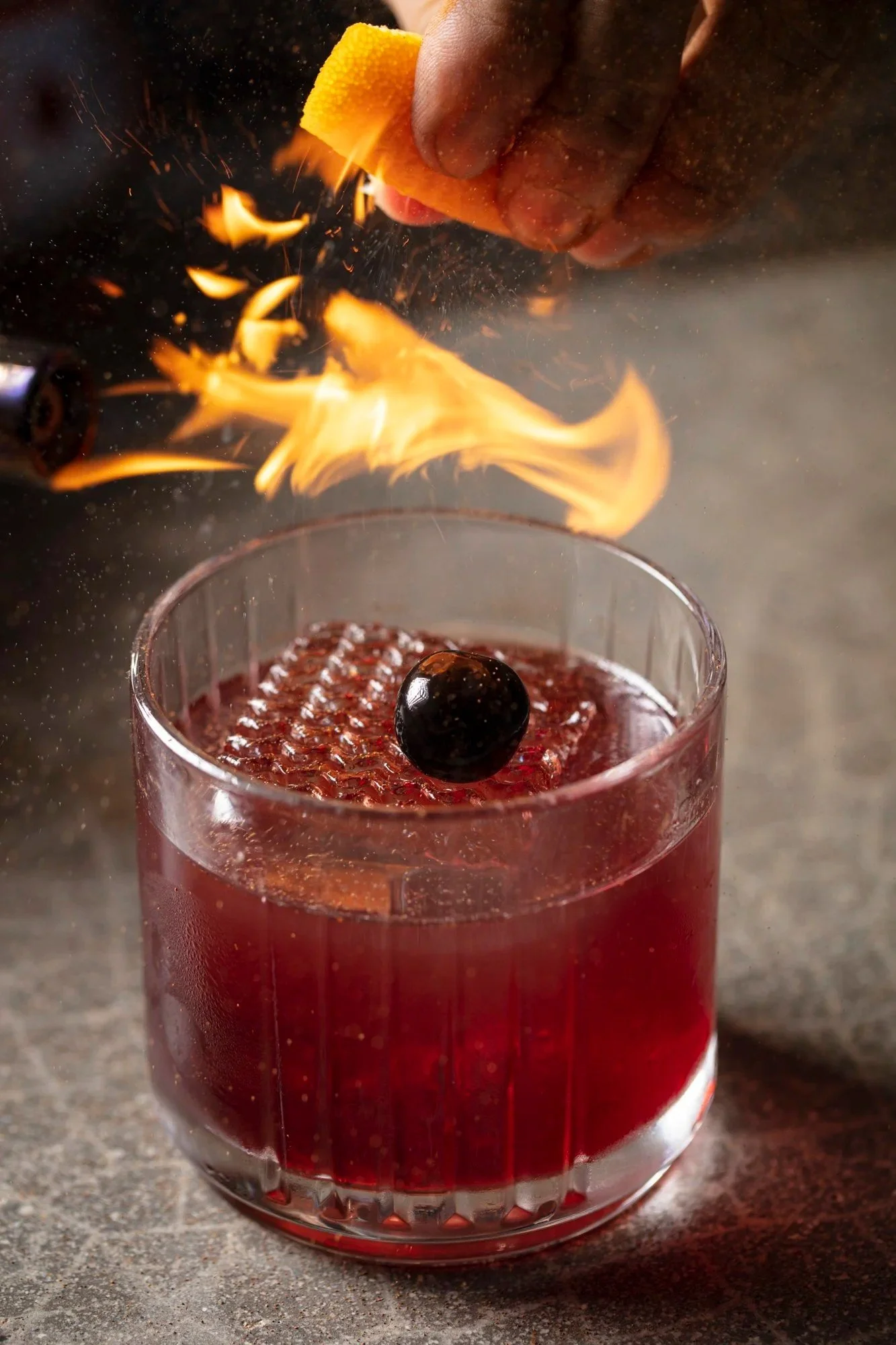 Flaming cocktail with a cherry garnish - beverage and cocktail photography